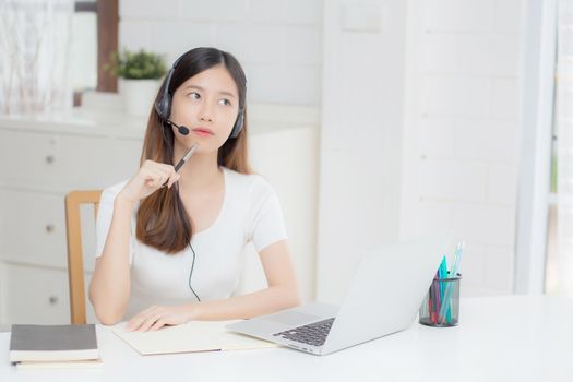 Young asian woman wearing headphone study online with e-learning on desk, girl wearing headset learning to internet with laptop computer at home, new normal, distance education and training.