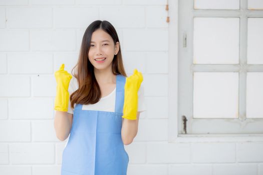 Portrait young asian woman is housekeeper in rubber gloves and apron for protection at home, uniform of maid, cleaning and washing, girl standing worker positive, one people, lifestyle concept.