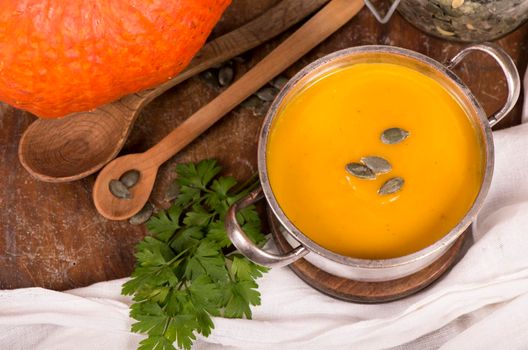 Bowl of pumpkin soup on rustic wooden background.