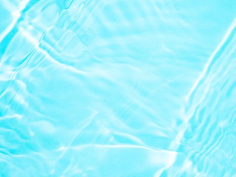 Ripple water texture on blue pool background. Shadow of water on sunlight. Mockup for product, spa or travel background. Marble blue water surface as wallpaper background
