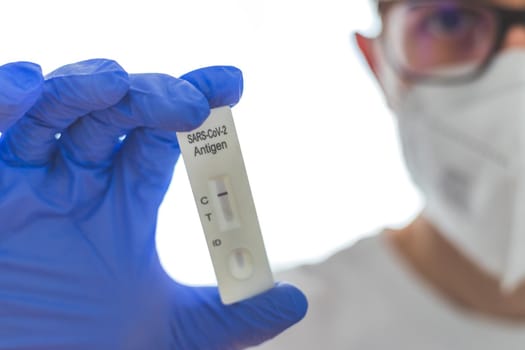 Close up of antigen corona or covid-19 test in the fingers of a young biologist or pharmacist