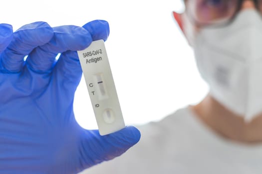 Close up of antigen corona or covid-19 test in the fingers of a young biologist or pharmacist