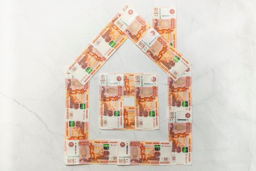 a house made of five-thousand-dollar bills on a marble background. High quality photo