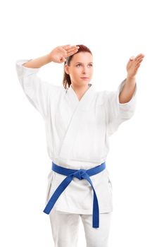 Portrait of a beautiful focused young female martial arts athlete in white kimono and blue belt in a fighting stance, isolated on white background. Martial arts concept.