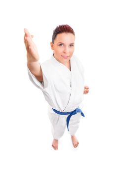 Top-down full body portrait of a beautiful young female fighter in white kimono smiling, isolated on white background. Girl in white kimono with blue belt. Martial arts concept.