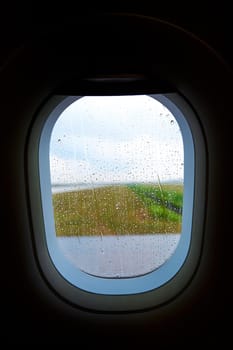 The interior of a passenger plane before takeoff. Porthole in raindrops.