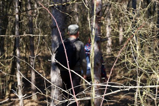 a man and a girl with backpacks make their way through a dense forest.