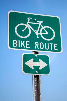 Green cyclist route traffic sign on blue sky.