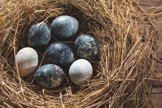 Easter composition - blue marble Easter eggs painted with natural dyes in a nest of hay.