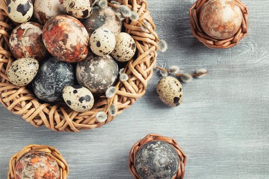 Easter composition - several marble eggs painted with natural dyes in a wicker nest and baskets, top view.