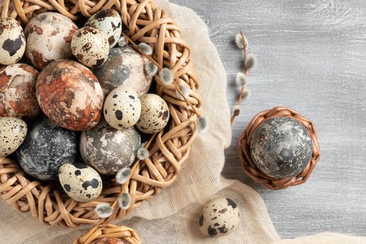 Easter composition - several marble eggs painted with natural dyes in a wicker nest and baskets, top view.