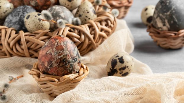 Easter composition - several marble eggs painted with natural dyes in a wicker nest and baskets.