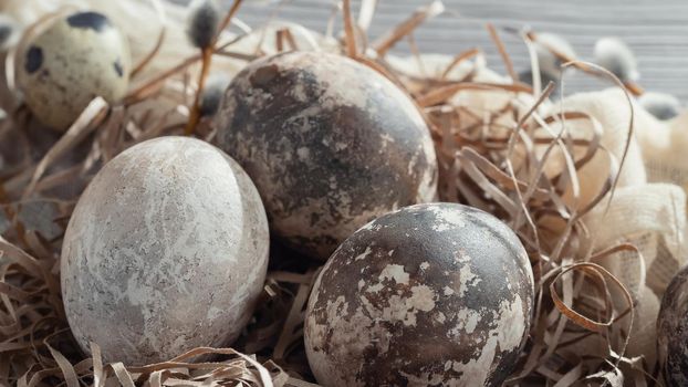 Easter composition - several marble eggs painted with natural dyes in a paper nest on the table.