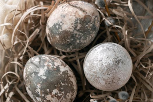 Easter composition - several marble eggs painted with natural dyes in a paper nest on the table, top view.