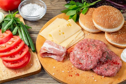 Process of cooking homemade burgers, meatballs, tomatoes, cheese and other ingredients on a wooden table, flat lay, top view.