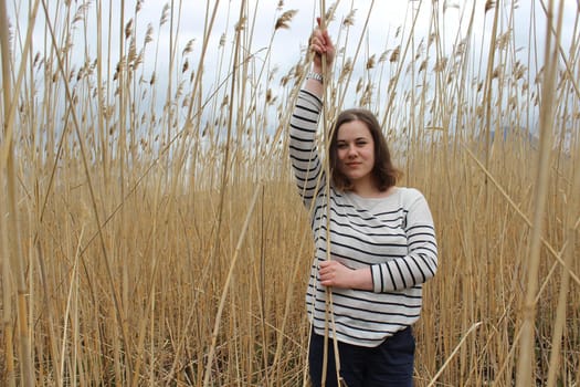 Portrait of a young girl in an outdoor field against a backdrop of wheat or tall grass. High quality photo