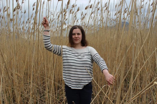 Portrait of a young girl in an outdoor field against a backdrop of wheat or tall grass. High quality photo