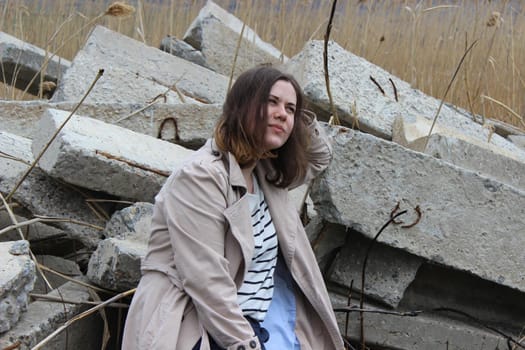 A portrait of an outdoor girl sits in a field on large concrete slabs. High quality photo