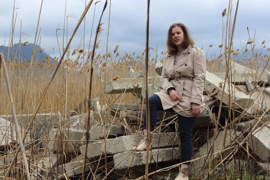 A portrait of an outdoor girl sits in a field on large concrete slabs. High quality photo