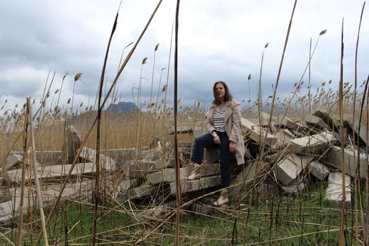 A portrait of an outdoor girl sits in a field on large concrete slabs. High quality photo