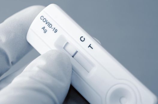 Hand in medical gloves is holding negative antigen rapid test for capturing of COVID-19 antibodies. It shows negative result. 