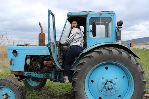 The girl on the tractor in the field. Plow the tractor land in the fall. Agricultural work. High quality photo