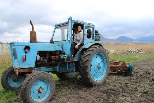 The girl on the tractor in the field. Plow the tractor land in the fall. Agricultural work. High quality photo