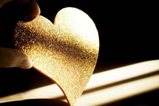 Golden shiny heart on black background