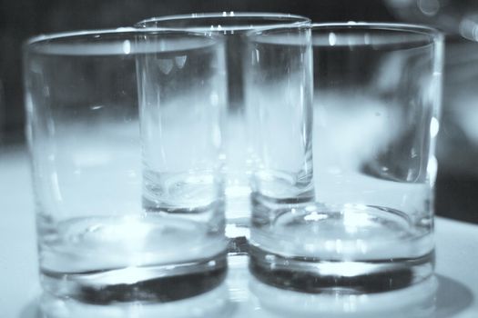 Three empty crystal glasses on dark background. No people