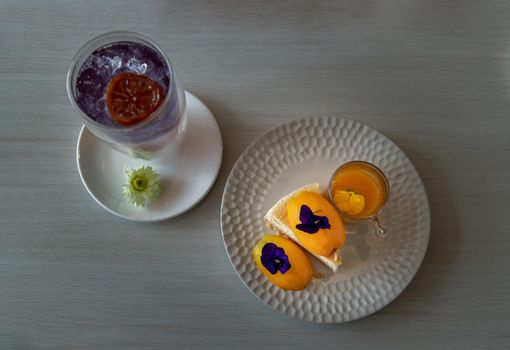 Glass of Lemonade with Slice of Mayomgchid cheesecake on white plate at cafe. Leisure, Food and drink, Copy space for text, Selective focus.