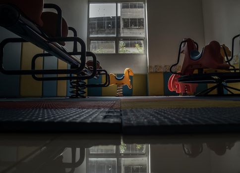 Empty yellow spring rider in children's playing playground room. Dark tone, Selective focus.