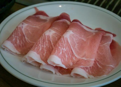 Sliced pork shoulder and streaky pork bacon are beautifully arranged on plate ready for grill on stove serve. Korean style barbecue. Selective focus.