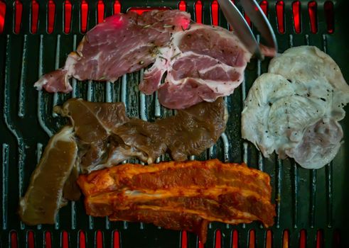 Marinated pork meat and Streaky pork grilling on stove serve. Korean style barbecue. Top view, No focus, specifically.