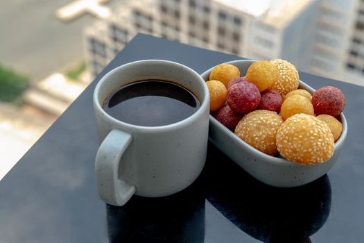 Breakfast Served in the morning with Hot black coffee with Fried Sweet Potato Balls with sesame, Deep fried purple and yellow sweet potato balls on black table. Selective focuse.