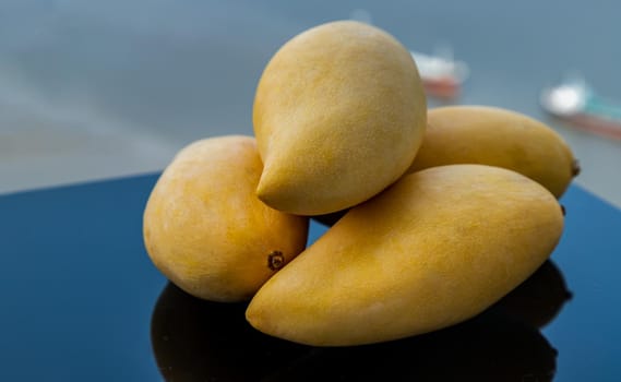 Ripe yellow barracuda mango fruit (Nam Dok Mai) on black table background. Tropical healthy fruit background, Selective focus.