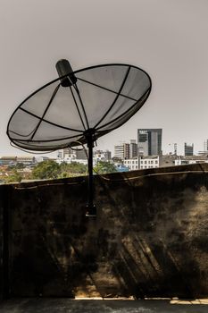 Black Satellite Dish Antenna Receiver at balcony house overlooking the urban view. No focus, specifically.