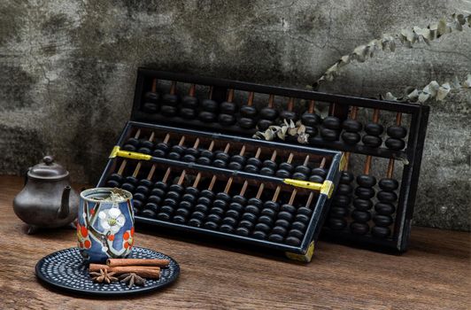 Chinese herbal tea and Vintage wooden hand abacus over Old wood table. Old chinese style atmosphere. Dark tone, Selective focus.