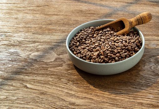 Coffee beans with old wooden scoop on the ceramic plate put on wooden background with copyspace for your text. Alternative coffee for living life, Coffee style, Selective focus.