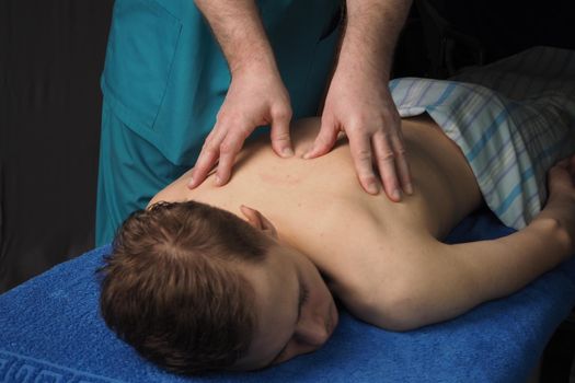 The back massage is manual. The specialist massages the back of the patient lying on the massage couch. High quality photo