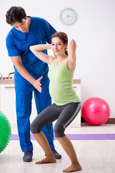 Pregnant woman doing physical exercies with instructor