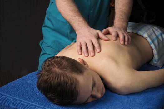 The back massage is manual. The specialist massages the back of the patient lying on the massage couch. High quality photo