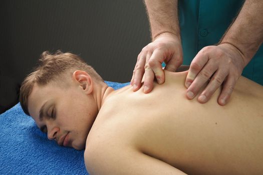 The back massage is manual. The specialist massages the back of the patient lying on the massage couch. High quality photo