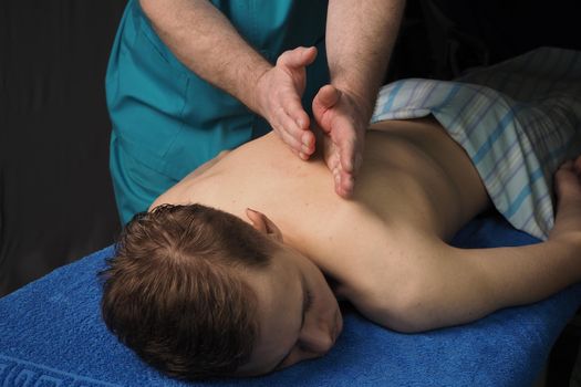 The back massage is manual. The specialist massages the back of the patient lying on the massage couch. High quality photo