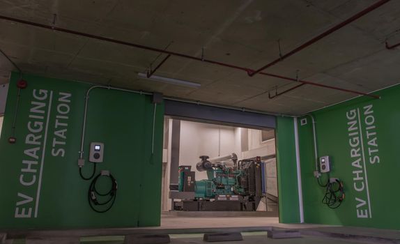 Bangkok, Thailand - 14 Jan 2021 : Front view of Generator Room Emergency power supply with service electric vehicle charging station and battery on the wall outside the room. Selective focus.