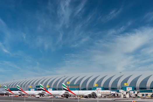 DUBAI, UAE - CIRCA 2021: Emirates Airline Airplanes parked on Dubai Airport, on cloudy sky background.
