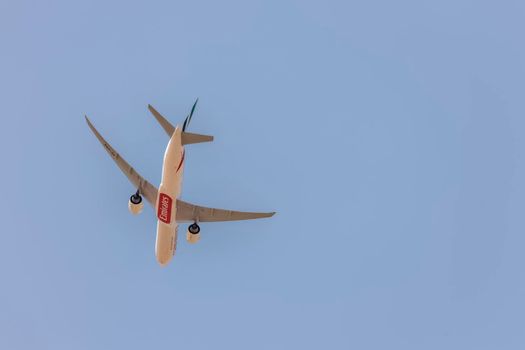 DUBAI, UAE - CIRCA 2021: Emirates Airline Boeing 777-31H(ER) Airplane isolated on blue clear sky making a turn before landing at Dubai International Airport