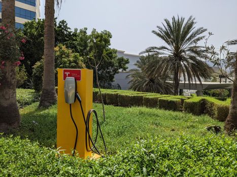 DUBAI, UAE - CIRCA 2021: Tesla Super Charger in the green area in front of a luxury hotel