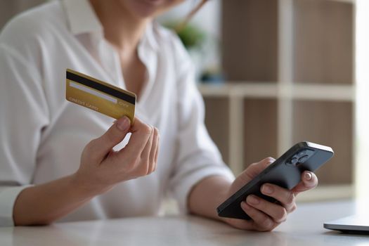 Woman paying with credit card on smart phone at home, online shopping concept