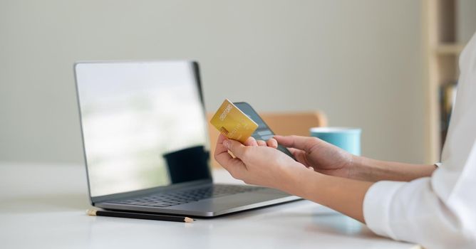 Close up hand of woman making card payment through mobile phone to pay bills.