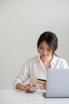 Attractive asian woman using her credit card for online shopping at home.